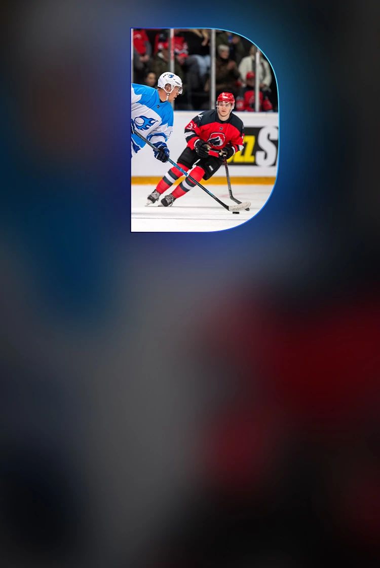 Two professional hockey players in action during a game, one in a red and black uniform and one in white and blue, on an ice rink with a cheering crowd.