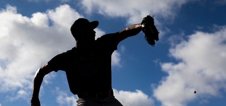 Baseball player pitching silhouette against sky background.